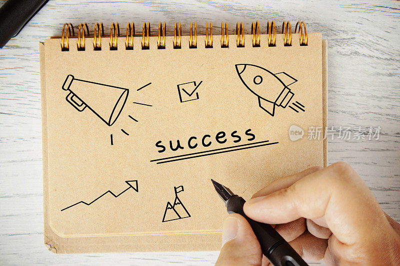 Businessman is drawing things about Success in notebook.